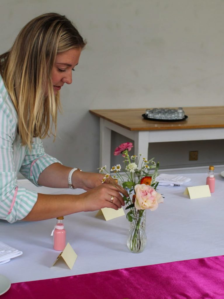 Megan Haigh florist arranging seasonal flowers in a small bud vase for a wedding table centrepiece by The Flowers of May, Cornwall wedding florist
